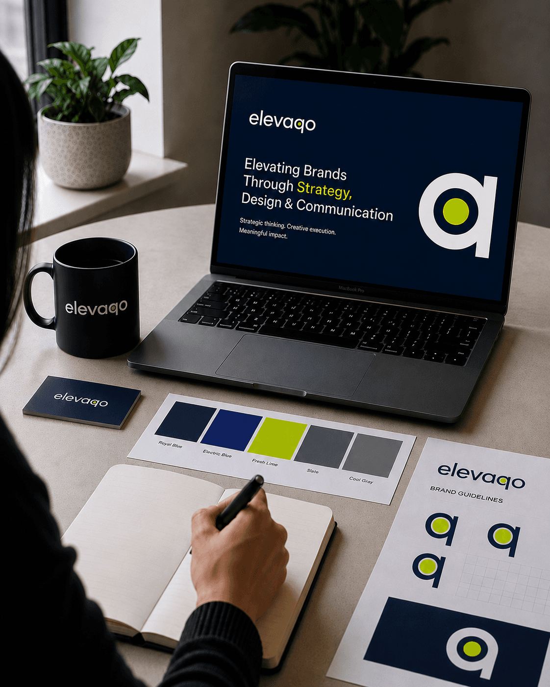 Elevaqo branded workspace with laptop, mug, colour palette and notebook